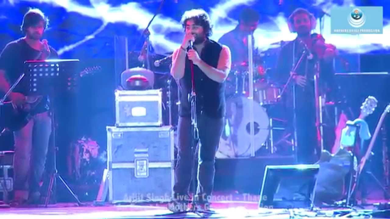 Arijit Singh performing live on stage with dynamic lighting and enthusiastic crowd