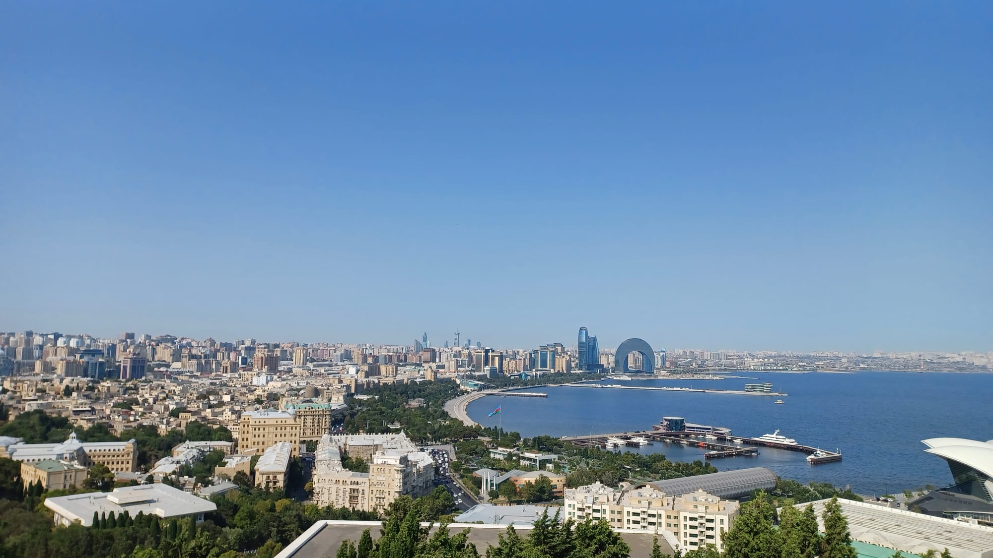 Panoramic view of Baku skyline showing Flame Towers and Caspian Sea at sunset
