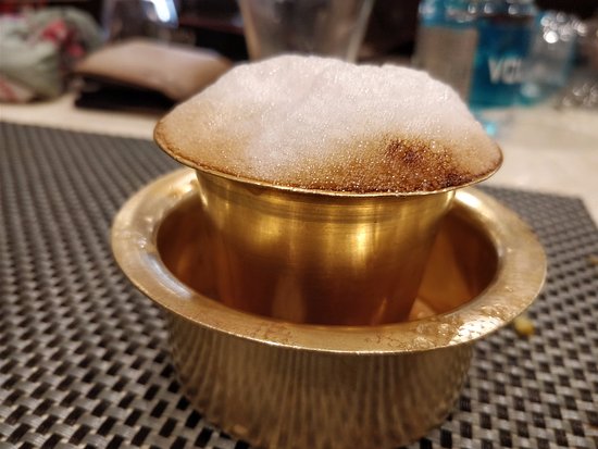Traditional South Indian filter coffee being served in metal tumbler