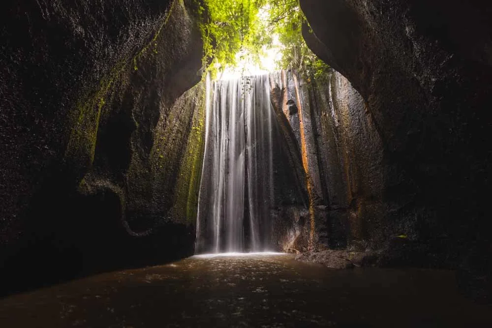 Sunlight beams entering Tukad Cepung Waterfall canyon in Bali