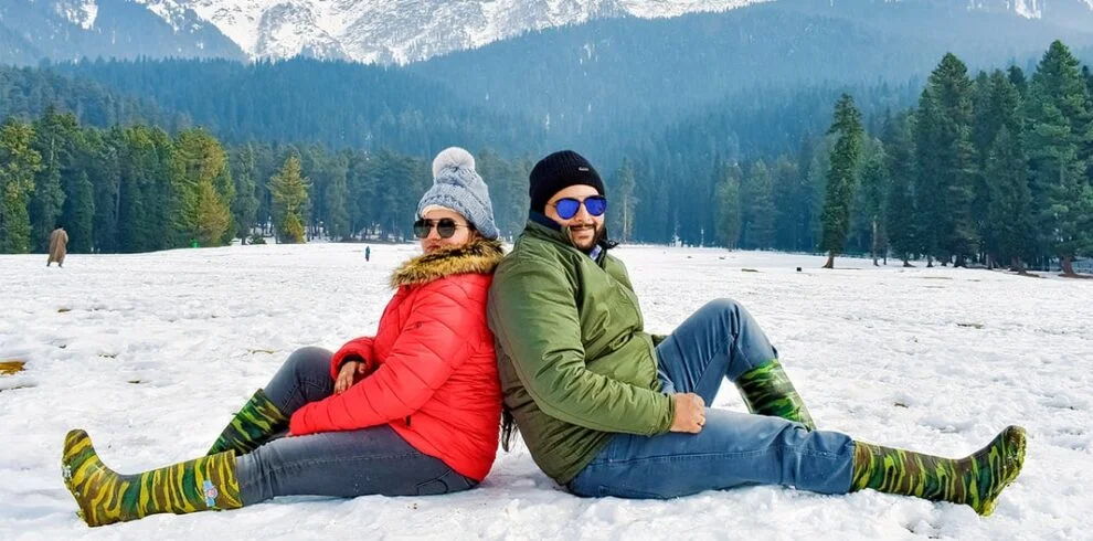 Tourist in Kashmir wearing traditional pheran with snow-capped mountains in background